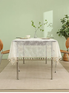 Close-up of white lace tablecloth with floral embroidery and tassel fringe details
