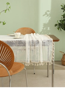 Close-up of white lace tablecloth featuring delicate leaf embroidery and elegant tassels