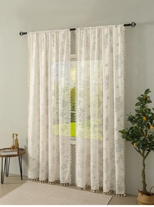 Detailed view of floral sheer curtains with fringe tassels on white translucent fabric