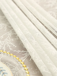 Detailed macro shot of white lace tablecloth with mesh patterns and elegant floral details