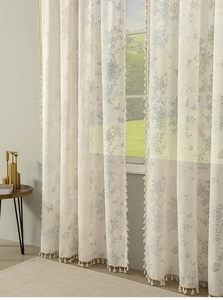 Detail of cream floral sheer curtain with elegant rose patterns and tassel fringe trim