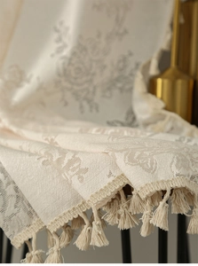 Detail of cream floral jacquard fabric with elegant tassel fringe for home decor