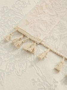 Detail of beige jacquard floral pattern fabric with elegant handmade tassels