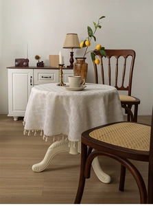 Close-up of thick linen round tablecloth with textured weave and delicate fringe edges