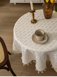 Macro detail of thick beige linen tablecloth featuring woven texture and fringe trim