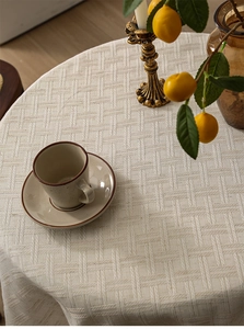 Macro view of beige jacquard tablecloth with textured grid pattern and tassels