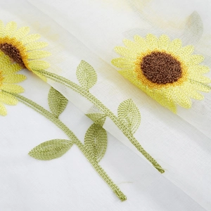 Detailed view of yellow daisy embroidery on white translucent tulle curtain fabric