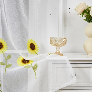 Close-up of intricate sunflower embroidery on semi-sheer white daisy towel fabric