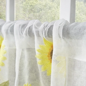 Close-up of white sheer curtain featuring yellow daisy floral embroidery and fabric texture