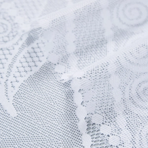 Detailed macro of white lace fabric with floral patterns and geometric mesh texture