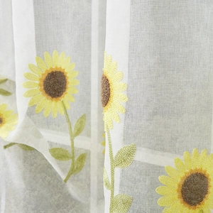 Close-up of daisy embroidery on white semi-sheer curtain with bright natural light