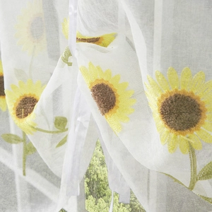 Macro shot of white daisy embroidery on semi-sheer curtain with elegant tie-up ribbon