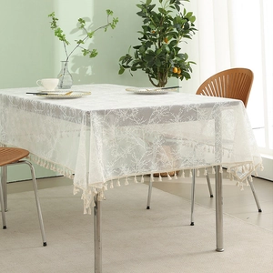 White lace tablecloth with tassel fringe and coral pattern on wooden dining table
