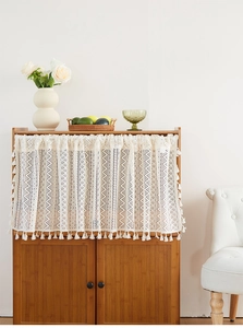 Detail of cream lace cafe curtain with tassel fringe and floral hollow pattern