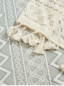 Detailed close-up of beige lace cafe curtain with delicate crochet patterns and fringe trim