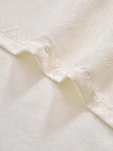 Detailed close-up of white damask jacquard curtain fabric with elegant scroll patterns