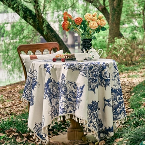 Detail of round French pastoral tablecloth with blue floral print and white tassel fringe