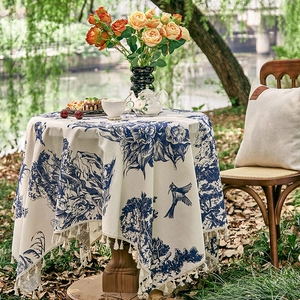 Detail of round French pastoral tablecloth with blue botanical print and ivory fringe