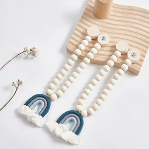 Dettaglio del fermatenda boho con perline in legno e nappe arcobaleno fatte a mano