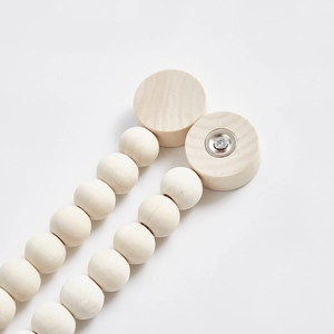 Dettaglio di perle in legno naturale e meccanismo a fibbia magnetica per tende