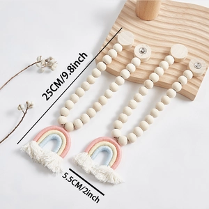 Dettaglio del ferma tende boho con arcobaleno, perline di legno e nappa in cotone bianco