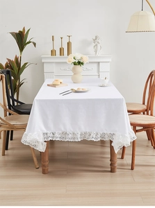 Macro-opname van wit waterdicht tafelkleed met kanten rand op houten tafel