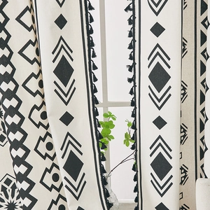 Detail of bohemian cotton linen curtain with black geometric patterns and tassel fringe