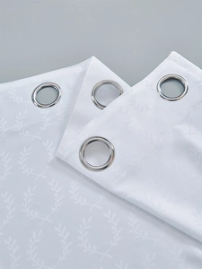 Detail of white blackout curtain featuring silver metal grommets and olive leaf jacquard texture