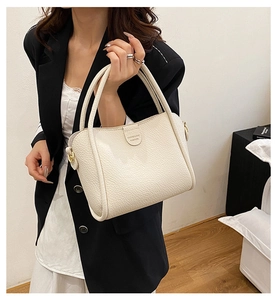 Detail of premium cream beige lychee leather tote bag with elegant cylindrical handles