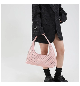 Detail of pink patent leather hobo bag featuring silver round metal rivets and top handle