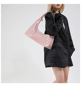 Pink patent leather underarm bag with silver metallic studs worn with a black blazer