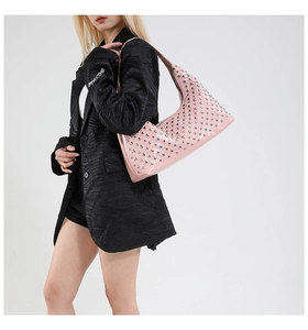 Detail of pink studded hobo bag on model featuring silver rivets and glossy finish
