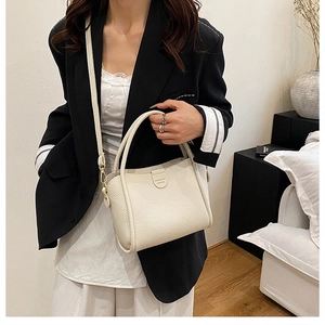Close-up of cream lychee texture leather bucket bag with golden hardware and strap