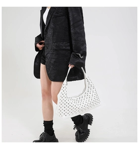 Detail of white leather hobo bag featuring polished silver rivet studs on a model