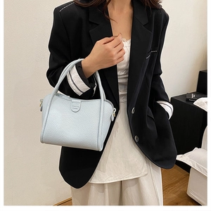 Detail of light blue bucket bag with pebble leather texture and gold metal accents