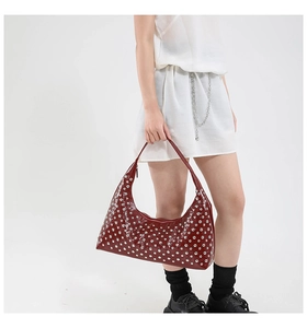 Detail of dark red patent leather hobo bag featuring silver punk rivets and chain