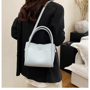 Detailed back view of a light blue leather bucket bag with top handles and shoulder strap