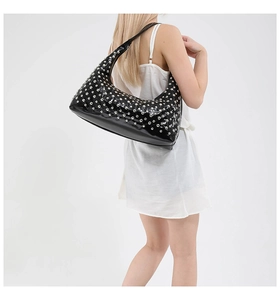 Close-up of black crescent shoulder bag with silver metal studs worn by a model