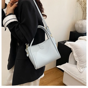 Detail view of the pebbled grey-blue leather texture and gold hardware hooks on bucket bag