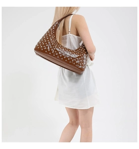 Detail of caramel brown hobo bag featuring dense silver studs and punk style crescent shape