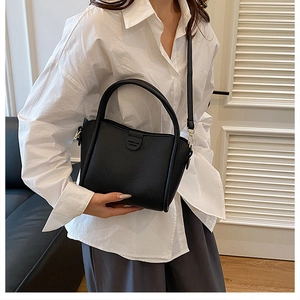 Detail of black lychee grain leather tote bag with round handles and embossed brand logo