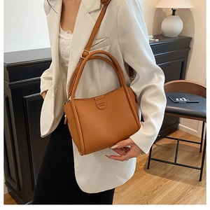 Caramel brown pebbled leather bucket bag styled with a white blazer in a chic interior