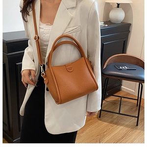 Detail of tan lychee pattern leather handbag with circular handles and shoulder strap