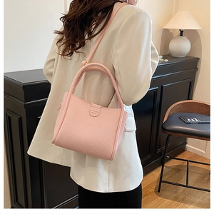 Detail of pink lychee grain leather bucket bag with brand logo and adjustable strap