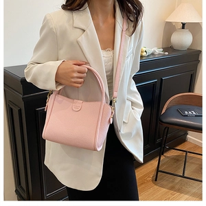 Pink lychee grain leather bucket bag with a top handle and adjustable strap detail