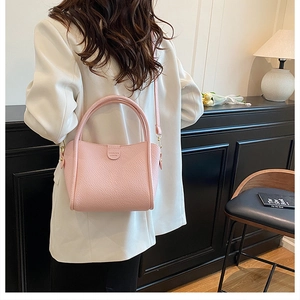 Detailed macro view of pink litchi grain leather texture and magnetic flap on bucket bag