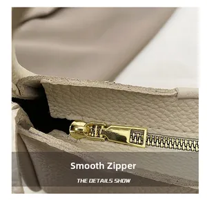 Detailed macro of smooth gold zipper and lychee pattern leather on beige bucket bag