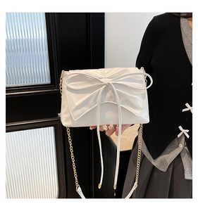Detail of white bow shoulder bag with golden chain strap and leather texture