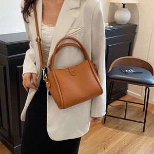 Brown lychee leather bucket bag with top handles and adjustable shoulder strap
