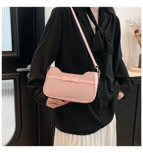 Dettaglio della borsa baguette rosa con trama intrecciata e fibbia decorativa a fiocco